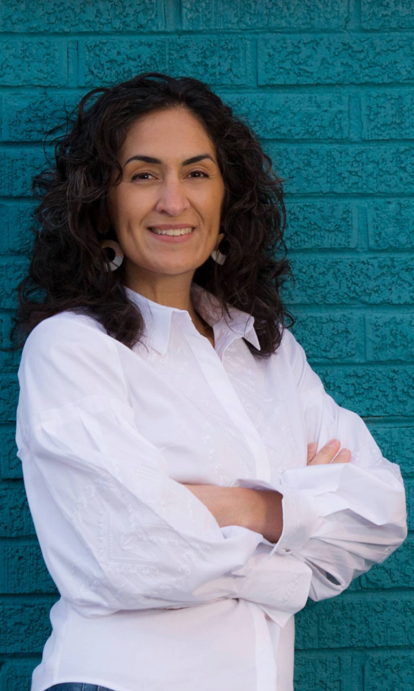 Photo of Carolynn Aristone standing in front of a blue wall